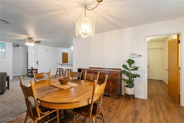 dining room featuring hardwood / wood-style floors, ceiling fan with notable chandelier, and a textured ceiling