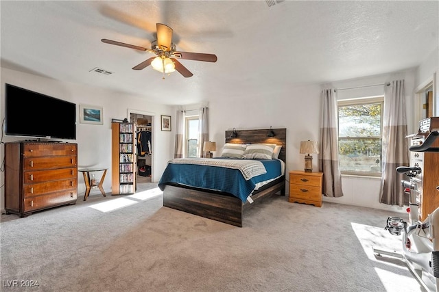 carpeted bedroom featuring a spacious closet, a closet, ceiling fan, and a textured ceiling