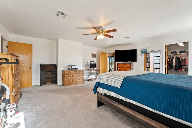 bedroom featuring light carpet, a walk in closet, a closet, and ceiling fan