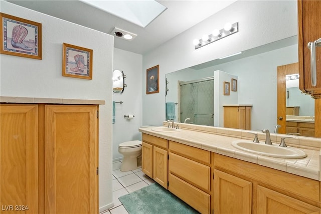 bathroom with a skylight, vanity, tile patterned flooring, toilet, and a shower with shower door