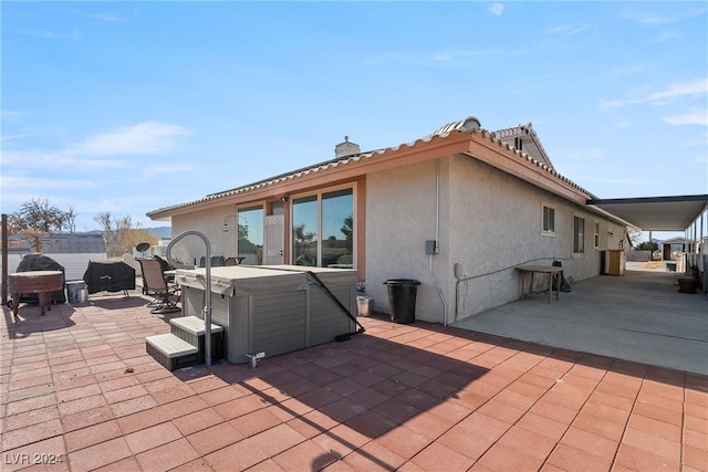 rear view of property with a patio and a hot tub