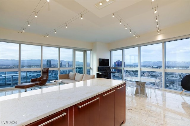 kitchen with a mountain view, light stone countertops, and rail lighting