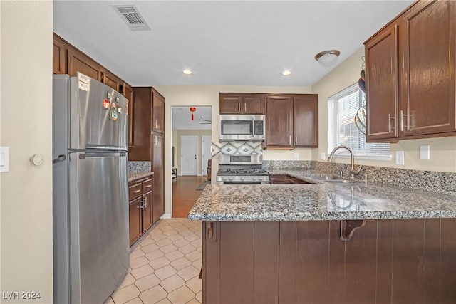 kitchen featuring stone counters, sink, light tile patterned flooring, kitchen peninsula, and stainless steel appliances