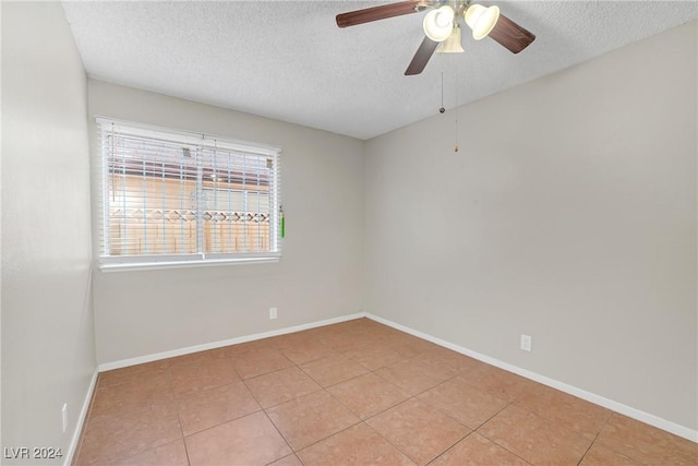 tiled empty room with ceiling fan and a textured ceiling