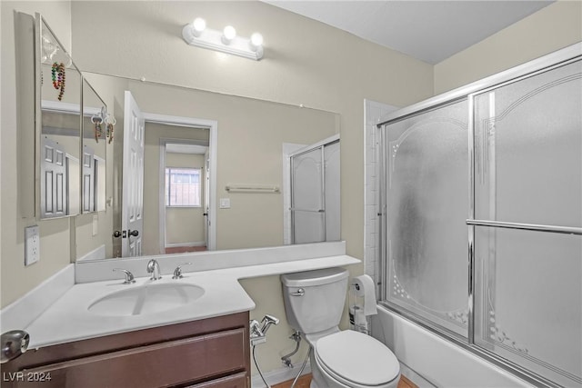 full bathroom with vanity, enclosed tub / shower combo, and toilet