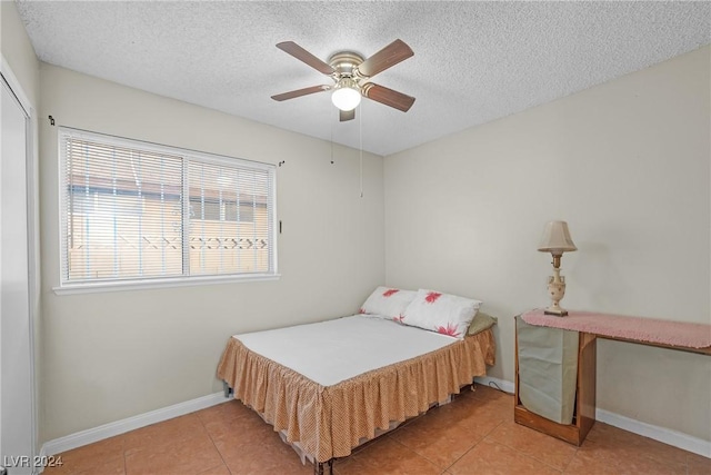 bedroom with tile patterned flooring, ceiling fan, and a textured ceiling