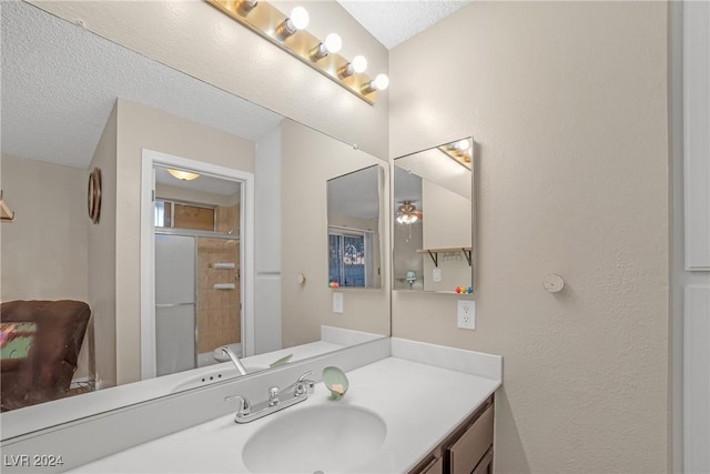 bathroom featuring vanity, a textured ceiling, and a shower with shower door