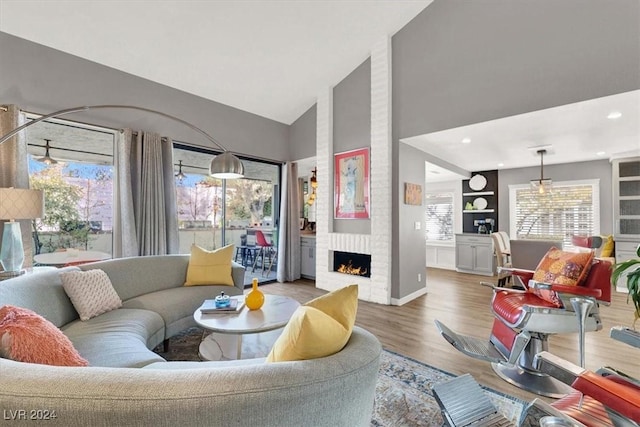 living room featuring high vaulted ceiling, wood-type flooring, and a brick fireplace