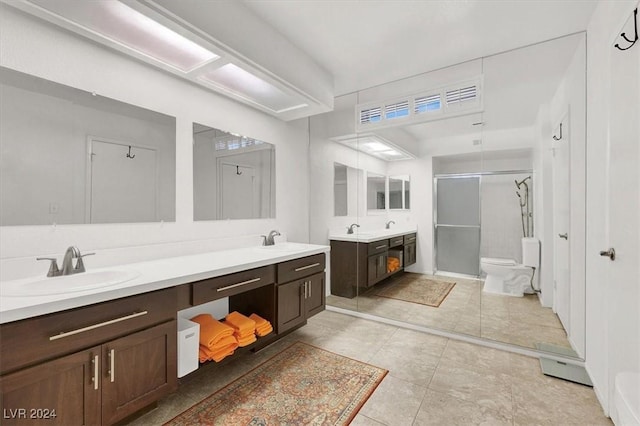 bathroom featuring tile patterned floors, vanity, toilet, and a shower with door