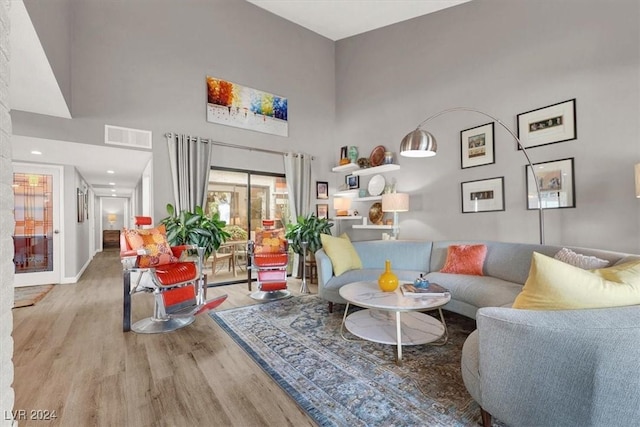 living room featuring a towering ceiling and light hardwood / wood-style flooring