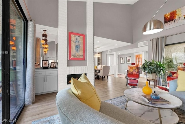 living room with a fireplace, a towering ceiling, and light hardwood / wood-style floors