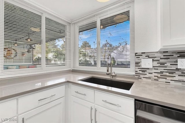 kitchen featuring tasteful backsplash, white cabinetry, sink, and dishwasher