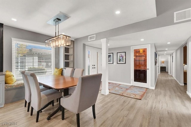 dining area with light hardwood / wood-style floors and ornate columns