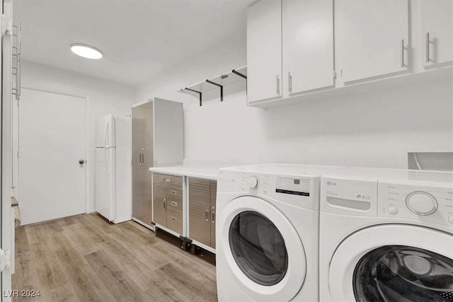 clothes washing area with cabinets, washing machine and dryer, and light hardwood / wood-style flooring