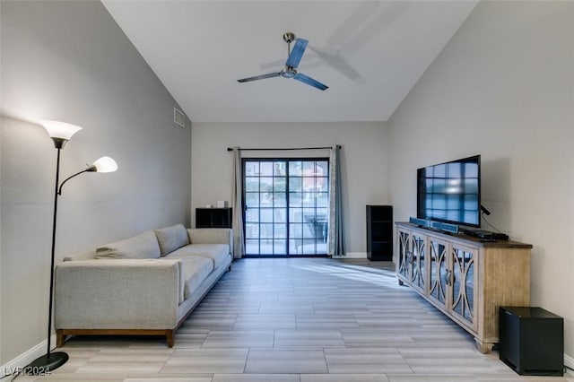 living room with ceiling fan, vaulted ceiling, and light wood-type flooring