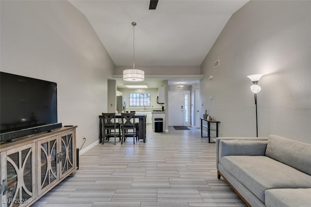 living room with vaulted ceiling, light hardwood / wood-style floors, and a chandelier