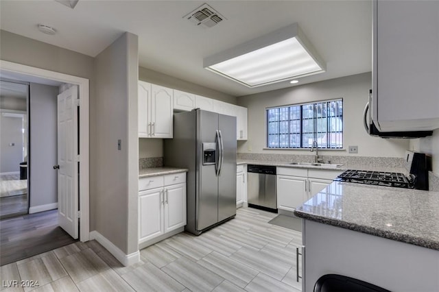 kitchen featuring white cabinets, sink, light stone countertops, light hardwood / wood-style floors, and stainless steel appliances