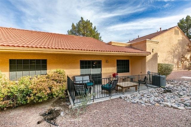 rear view of property with a patio area, outdoor lounge area, and central AC