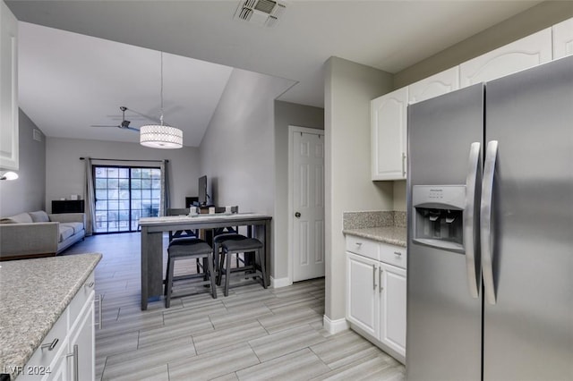 kitchen featuring white cabinets, stainless steel fridge, vaulted ceiling, and pendant lighting