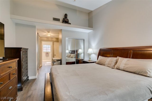 bedroom featuring hardwood / wood-style flooring, a closet, a high ceiling, and ensuite bath