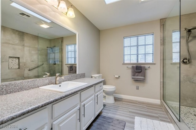 bathroom with toilet, hardwood / wood-style floors, vanity, and tiled shower