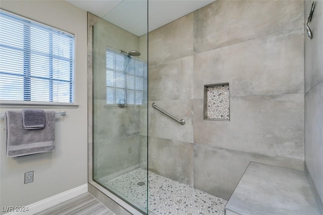 bathroom with a tile shower and wood-type flooring