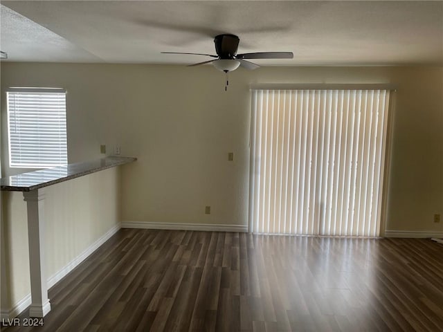 unfurnished living room with a textured ceiling, ceiling fan, and dark wood-type flooring