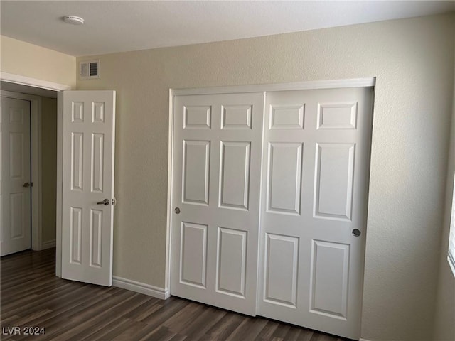 unfurnished bedroom featuring a closet and dark hardwood / wood-style floors