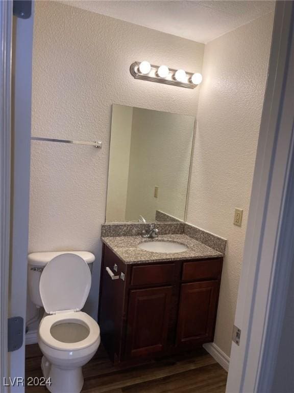 bathroom featuring wood-type flooring, vanity, and toilet