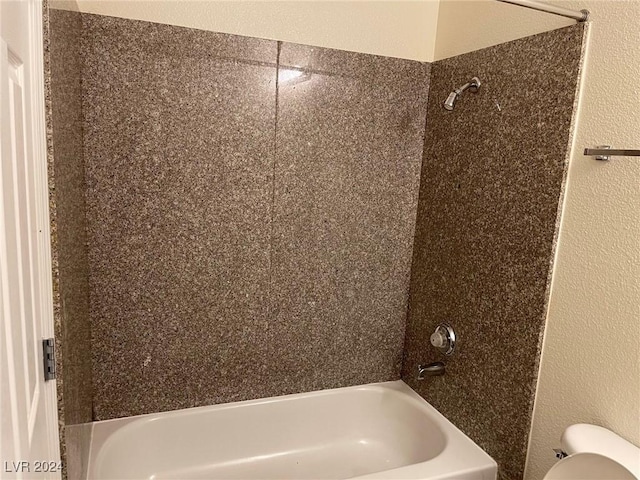 bathroom featuring toilet and tiled shower / bath