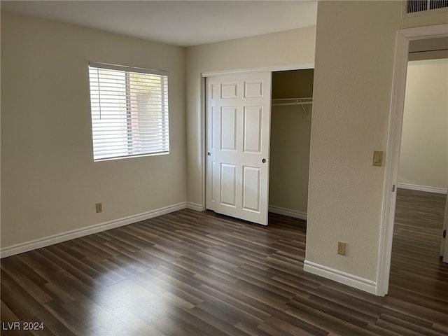 unfurnished bedroom with dark hardwood / wood-style flooring and a closet