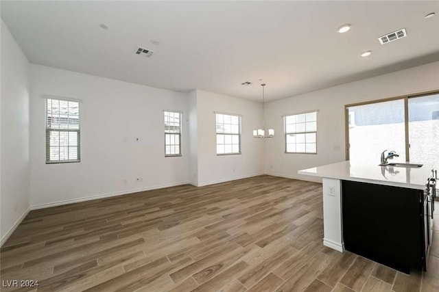 kitchen featuring sink, hanging light fixtures, a notable chandelier, and hardwood / wood-style flooring