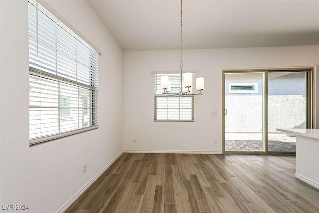 unfurnished dining area featuring a chandelier, hardwood / wood-style flooring, and a wealth of natural light