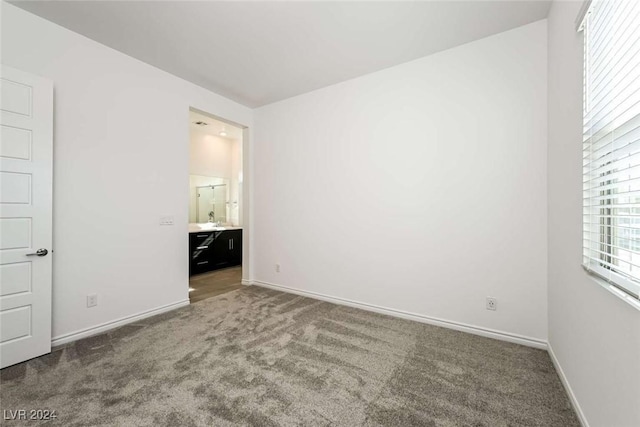 unfurnished bedroom featuring carpet floors, sink, and ensuite bath