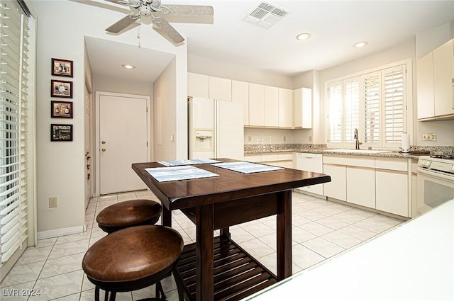 kitchen with white appliances, sink, ceiling fan, light tile patterned floors, and white cabinetry