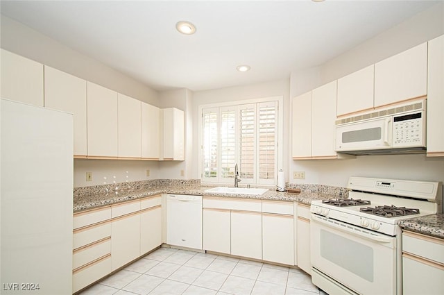 kitchen with white cabinetry, sink, light tile patterned floors, and white appliances