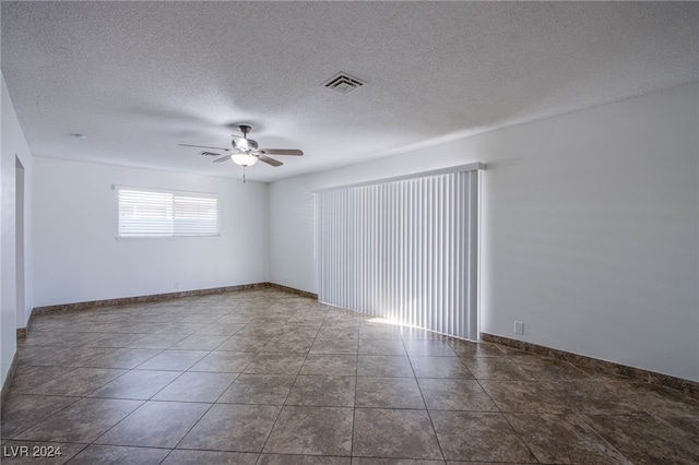 tiled empty room featuring ceiling fan and a textured ceiling