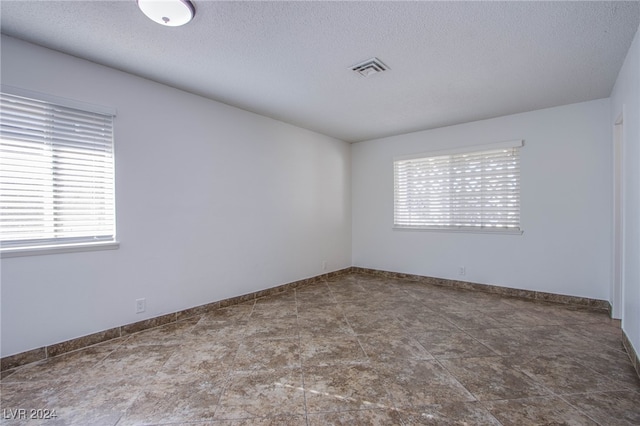 unfurnished room with a textured ceiling