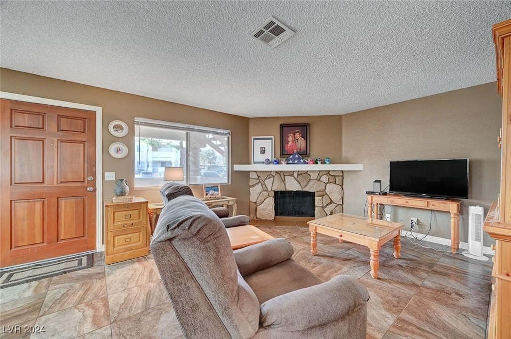 living room featuring a stone fireplace and a textured ceiling