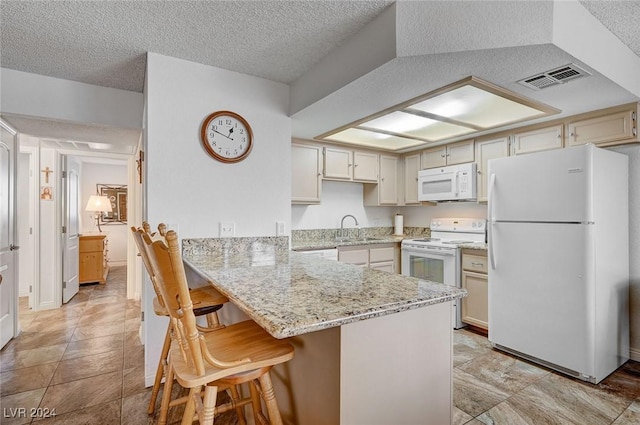 kitchen with sink, white appliances, light stone counters, a kitchen bar, and kitchen peninsula