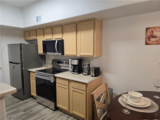 kitchen with light brown cabinets, light hardwood / wood-style flooring, and appliances with stainless steel finishes