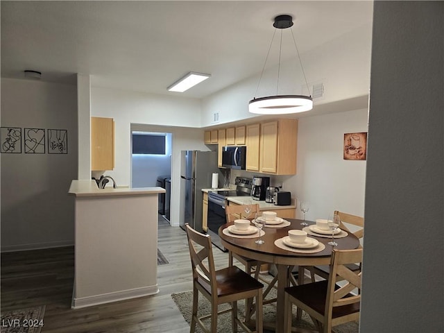 kitchen with dark wood-type flooring, sink, light brown cabinetry, appliances with stainless steel finishes, and decorative light fixtures