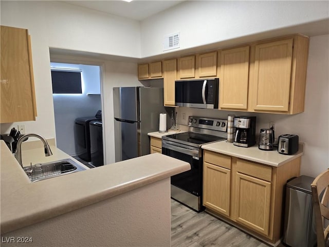 kitchen with sink, light brown cabinets, stainless steel appliances, light hardwood / wood-style flooring, and washer and dryer