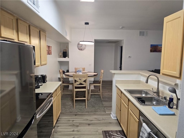 kitchen with light brown cabinets, sink, hanging light fixtures, stainless steel fridge, and range with electric stovetop