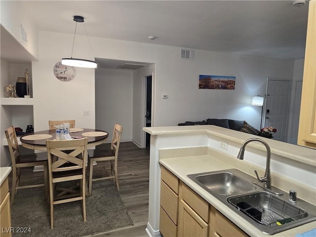 kitchen featuring light brown cabinets, sink, hanging light fixtures, and dark wood-type flooring