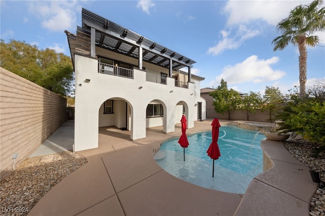 back of house featuring pool water feature, a patio area, a fenced in pool, and a balcony