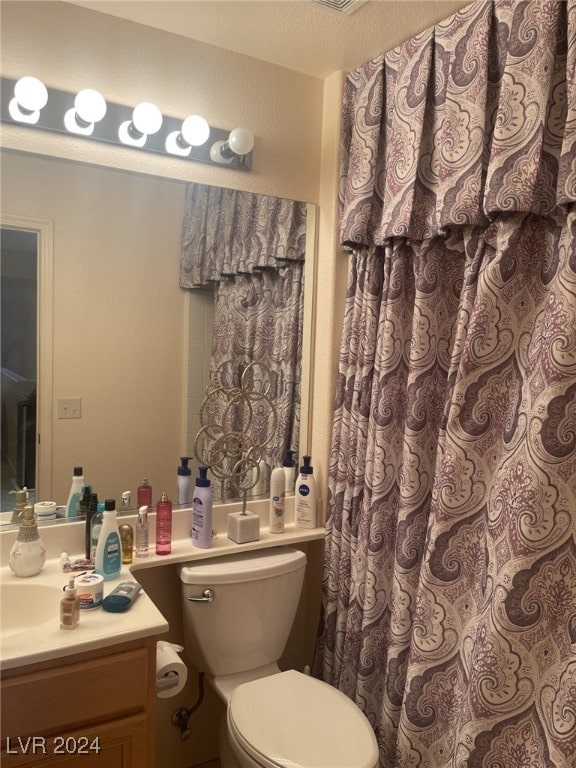 bathroom with a textured ceiling, vanity, and toilet