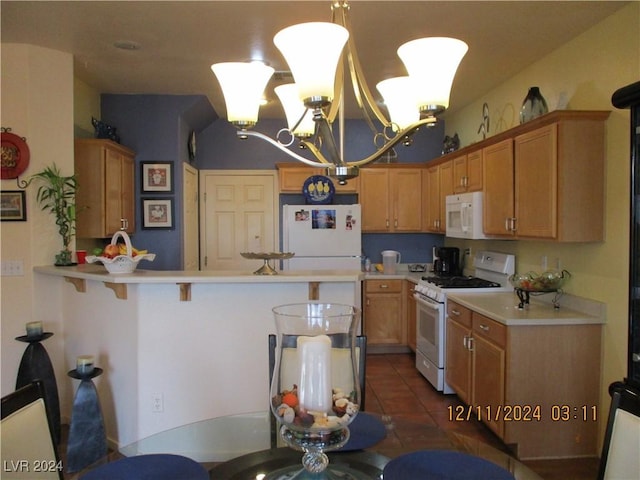 kitchen with white appliances, dark tile patterned flooring, a kitchen bar, kitchen peninsula, and a chandelier