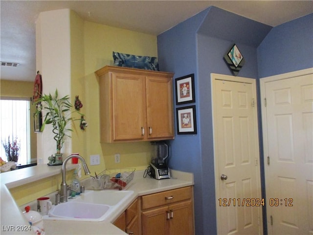 kitchen with kitchen peninsula, vaulted ceiling, and sink