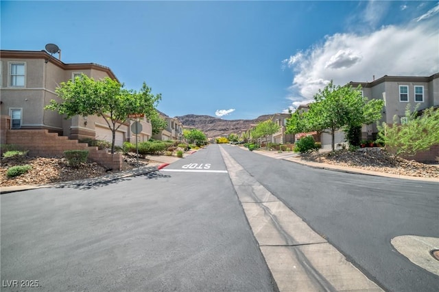 view of street featuring curbs, a mountain view, sidewalks, and a residential view